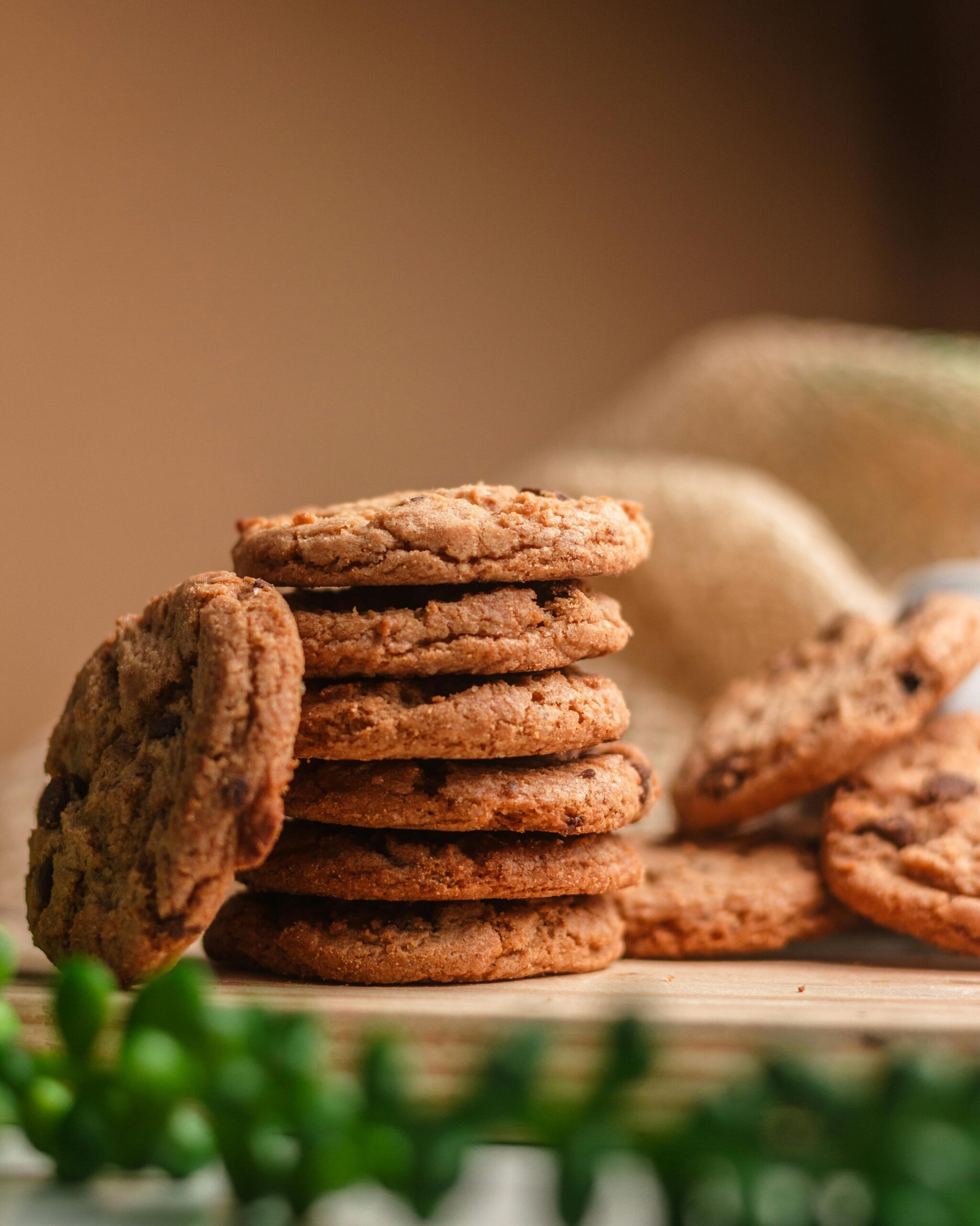 Freshly baked homemade chocolate chip cookies stacked on a wooden surface.